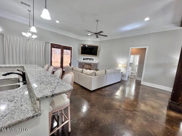 living room featuring ornamental molding, sink, ceiling fan with notable chandelier, and french doors