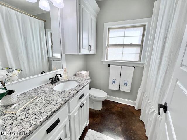 bathroom featuring vanity, concrete flooring, and toilet