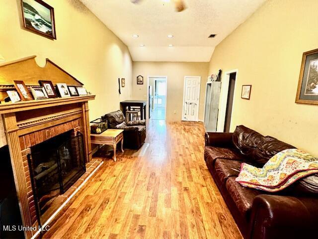 living room with lofted ceiling, wood-type flooring, and a fireplace