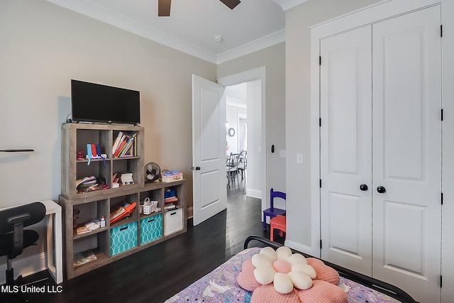 bedroom with ornamental molding, dark wood-type flooring, ceiling fan, and a closet