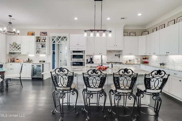 kitchen featuring white cabinetry, decorative light fixtures, light stone countertops, and beverage cooler