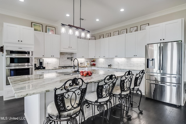 kitchen with light stone counters, decorative light fixtures, stainless steel appliances, and a spacious island