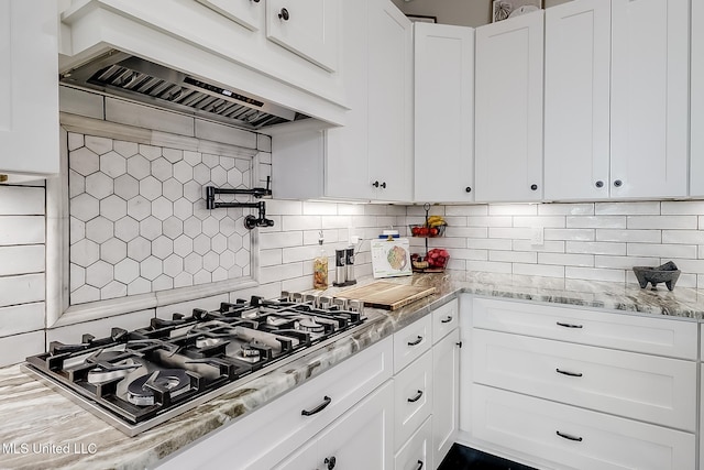 kitchen with white cabinets, decorative backsplash, stainless steel gas cooktop, light stone countertops, and custom range hood