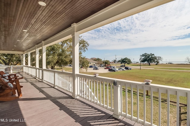 wooden terrace featuring a porch and a yard