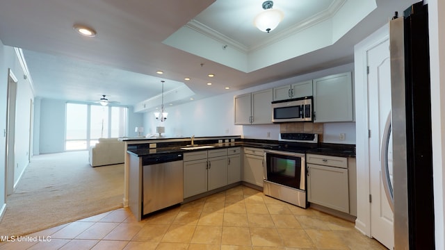 kitchen with kitchen peninsula, a raised ceiling, stainless steel appliances, gray cabinets, and light colored carpet