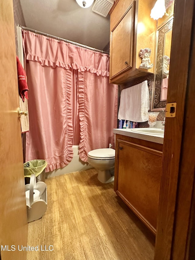 full bathroom with toilet, vanity, hardwood / wood-style flooring, and shower / tub combo with curtain