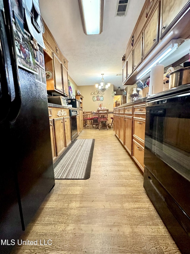 kitchen featuring black dishwasher, light hardwood / wood-style flooring, a chandelier, pendant lighting, and a textured ceiling