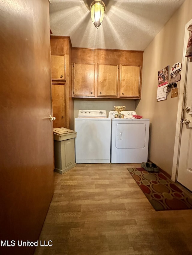 laundry room with cabinets, separate washer and dryer, a textured ceiling, and light hardwood / wood-style flooring