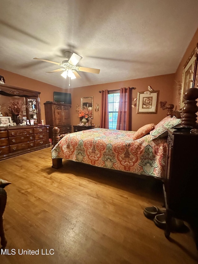 bedroom with a textured ceiling, light wood-type flooring, and ceiling fan