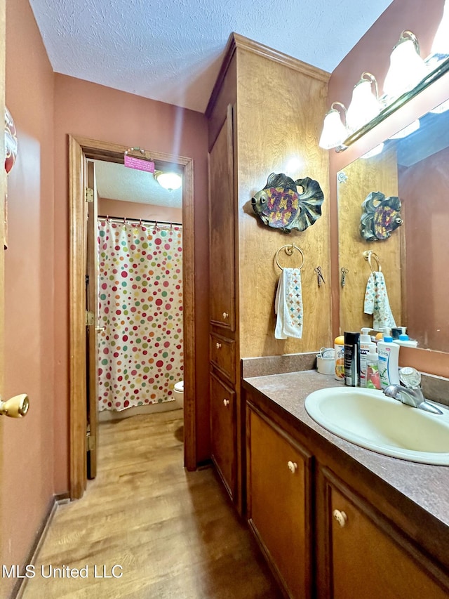 bathroom featuring toilet, vanity, a textured ceiling, and hardwood / wood-style flooring