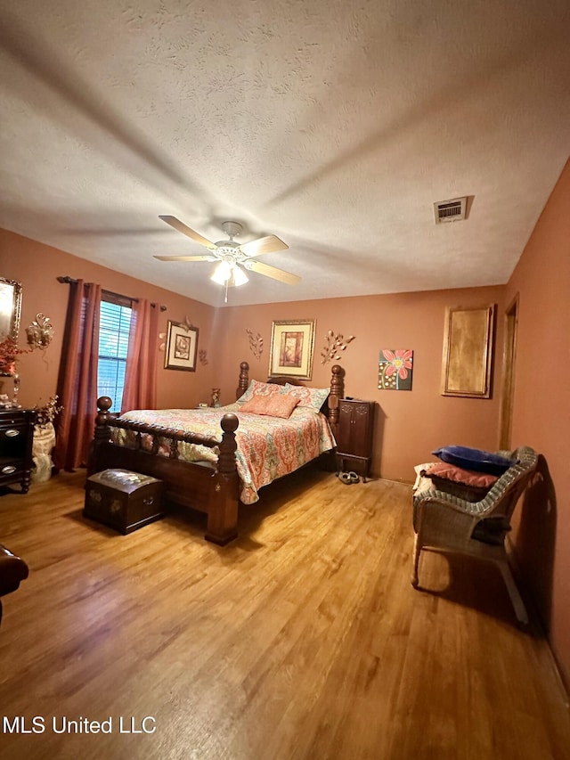 bedroom featuring ceiling fan, hardwood / wood-style floors, and a textured ceiling