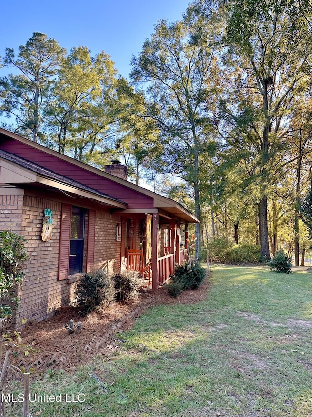 view of side of property with a porch and a lawn