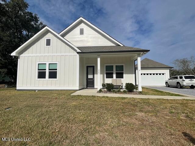 view of front of house with a front yard, a porch, and a garage