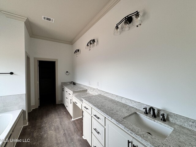 bathroom featuring ornamental molding, vanity, wood-type flooring, and a washtub