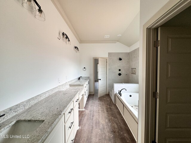 bathroom with wood-type flooring, lofted ceiling, a bathtub, vanity, and crown molding