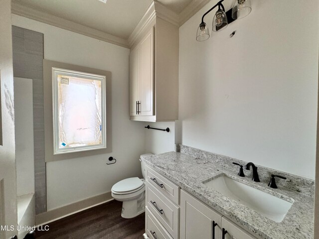 bathroom with hardwood / wood-style flooring, vanity, a bath, ornamental molding, and toilet