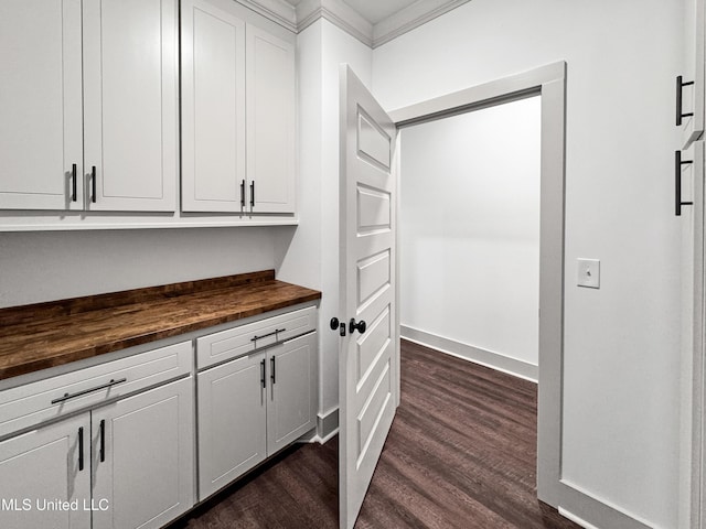 kitchen with white cabinetry, crown molding, butcher block countertops, and dark wood-type flooring