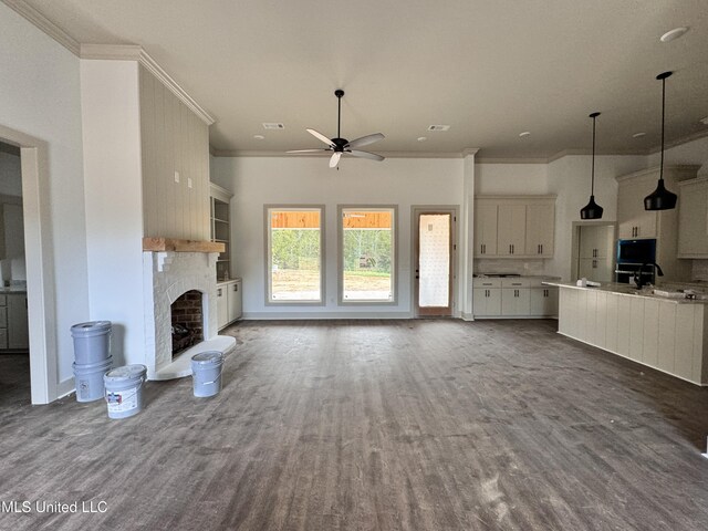 unfurnished living room featuring ornamental molding, dark wood-type flooring, ceiling fan, and a fireplace