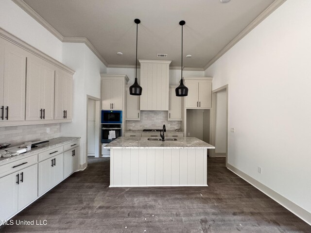 kitchen featuring pendant lighting, dark hardwood / wood-style floors, light stone countertops, an island with sink, and oven