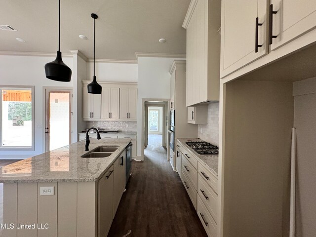 kitchen featuring white cabinetry, decorative light fixtures, light stone countertops, a kitchen island with sink, and decorative backsplash