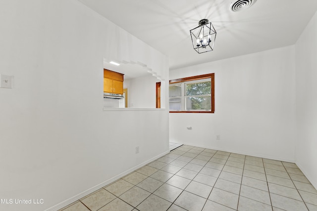 empty room with a notable chandelier and light tile patterned floors