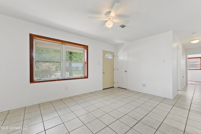 tiled spare room featuring a wealth of natural light and ceiling fan