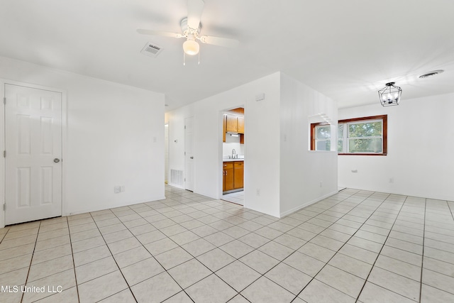 unfurnished room with sink, ceiling fan with notable chandelier, and light tile patterned floors