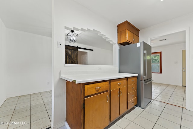 kitchen with stainless steel fridge, a barn door, and light tile patterned flooring