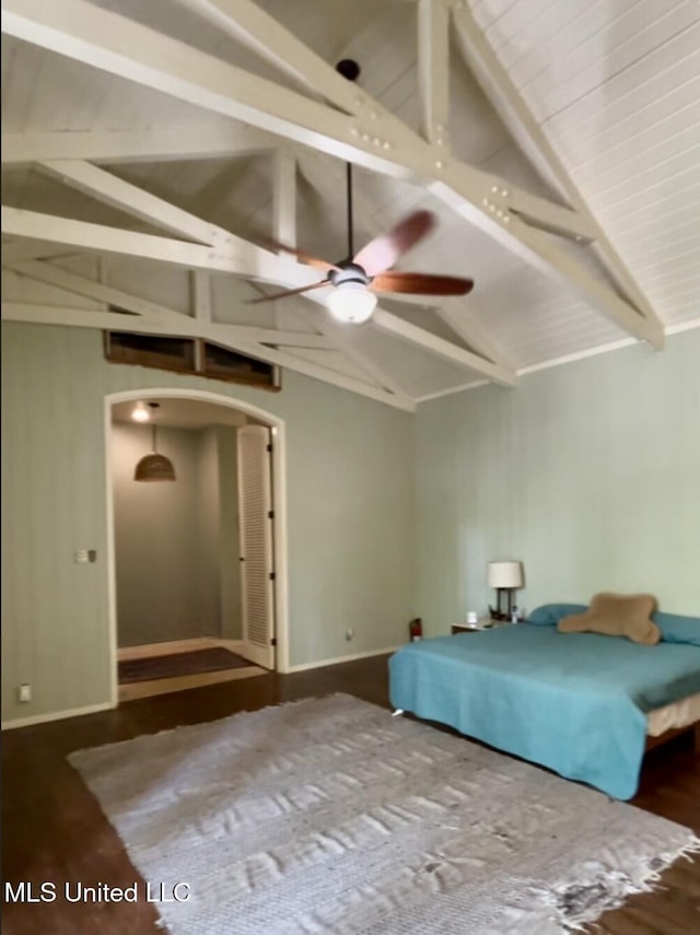 bedroom with baseboards, lofted ceiling with beams, arched walkways, and wood finished floors