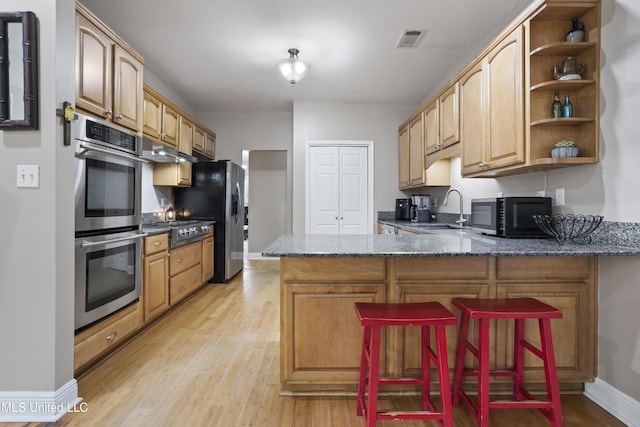 kitchen with stainless steel appliances, visible vents, a sink, dark stone countertops, and a peninsula