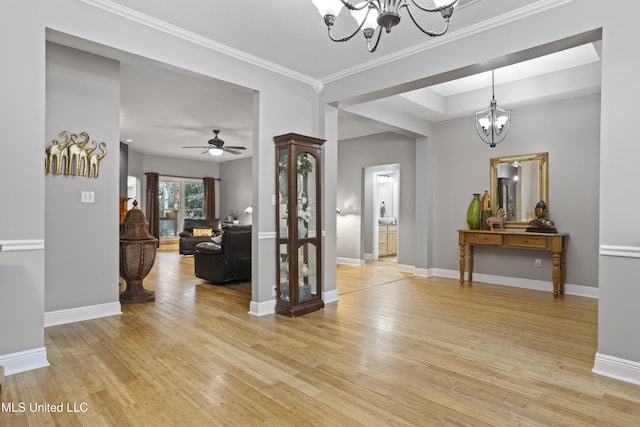 foyer entrance featuring baseboards, ornamental molding, ceiling fan with notable chandelier, and light wood-style floors