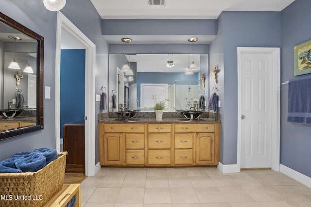 bathroom featuring double vanity, a stall shower, baseboards, tile patterned flooring, and a sink