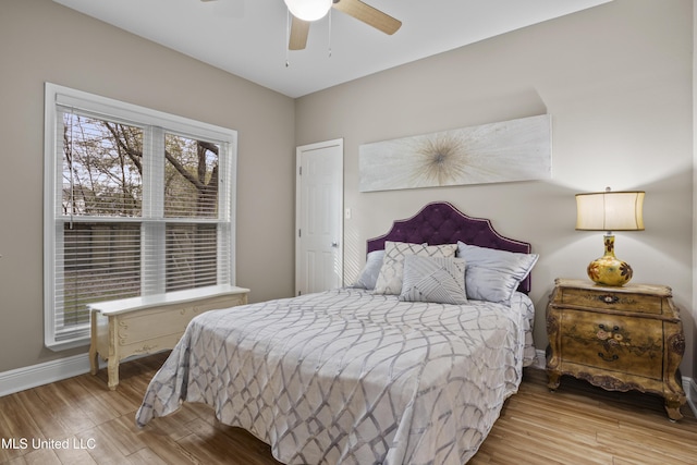 bedroom featuring a ceiling fan, baseboards, and wood finished floors