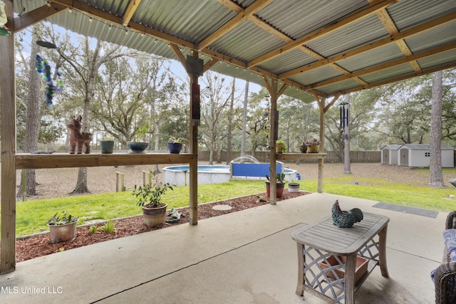 view of patio / terrace with fence, a storage unit, a fenced in pool, and an outdoor structure