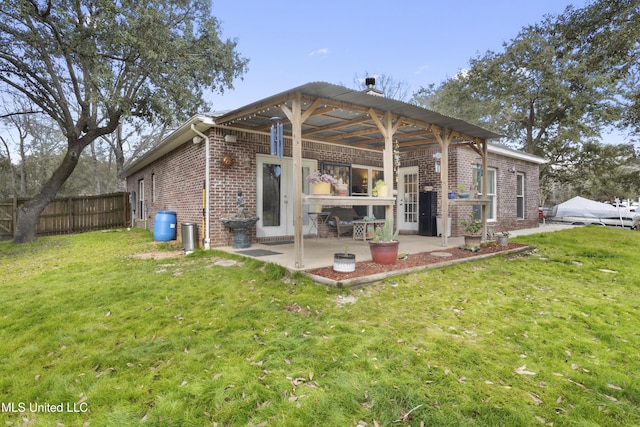 rear view of house featuring a patio area, a yard, fence, and brick siding