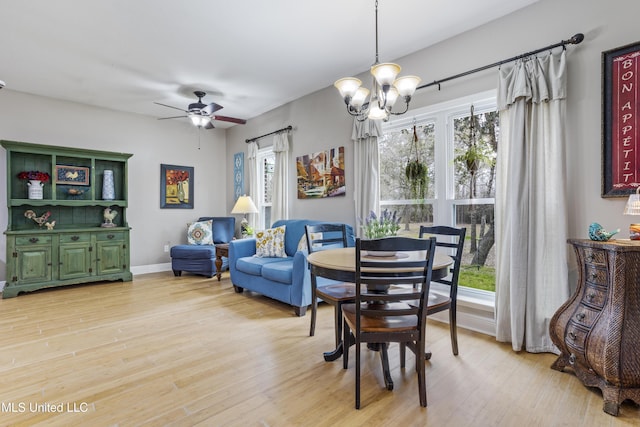 dining area with ceiling fan with notable chandelier, light wood finished floors, and baseboards