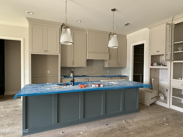 kitchen with decorative light fixtures, ornamental molding, visible vents, a center island with sink, and backsplash