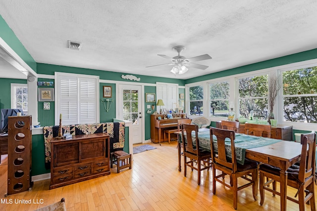 dining space with light hardwood / wood-style floors, a textured ceiling, and ceiling fan