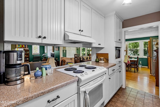 kitchen featuring light stone countertops, white cabinetry, light hardwood / wood-style floors, and white electric stove