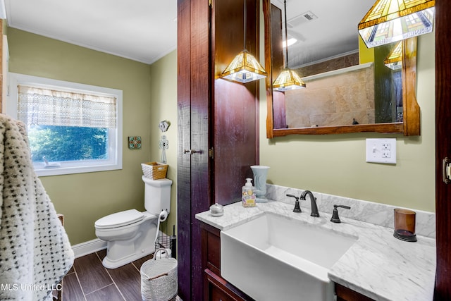 bathroom featuring vanity, hardwood / wood-style floors, crown molding, and toilet