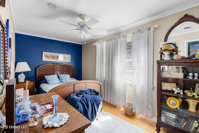 bedroom with ceiling fan, crown molding, and light hardwood / wood-style flooring