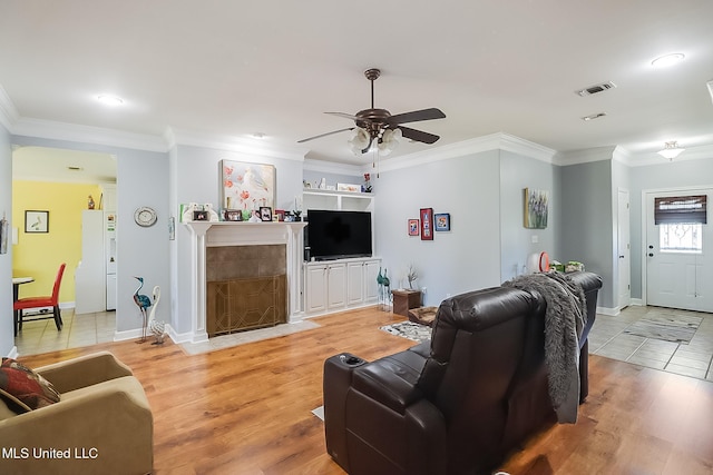 13061 Jordan Pl, Gulfport, MS 39503 - living area with ceiling fan, light wood finished floors, a tile fireplace, baseboards, and ornamental molding