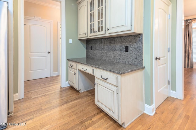 8679 Saddle Creek Dr, Olive Branch, MS 38654 - kitchen featuring light wood finished floors, decorative backsplash, built in desk, glass insert cabinets, and crown molding