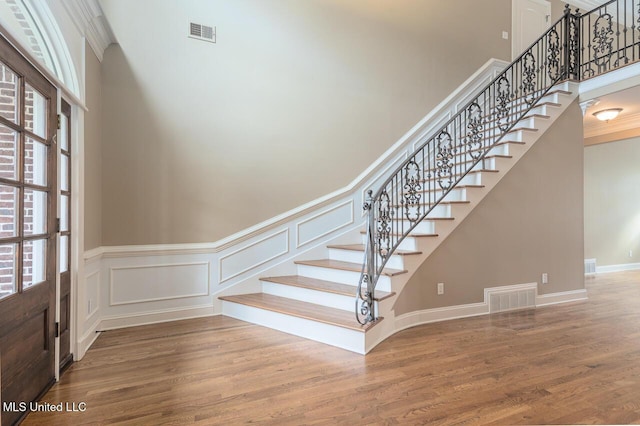 8679 Saddle Creek Dr, Olive Branch, MS 38654 - staircase featuring wood finished floors, a towering ceiling, a decorative wall, ornamental molding, and wainscoting
