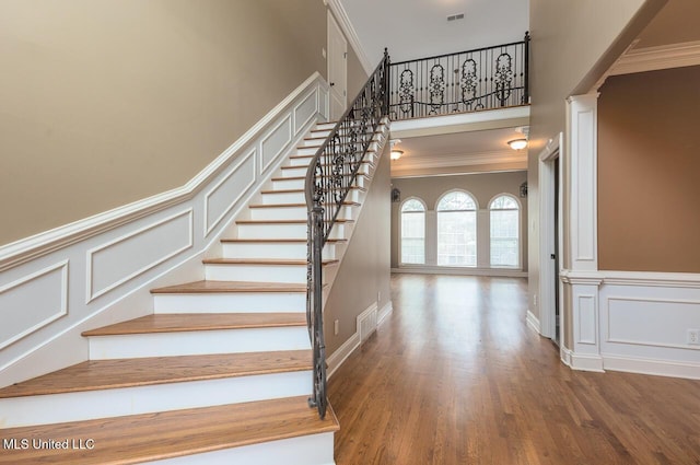 8679 Saddle Creek Dr, Olive Branch, MS 38654 - stairway with a decorative wall, crown molding, wood finished floors, wainscoting, and a high ceiling