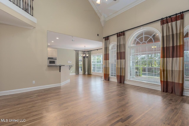 8679 Saddle Creek Dr, Olive Branch, MS 38654 - unfurnished living room featuring a chandelier, crown molding, a high ceiling, and wood finished floors