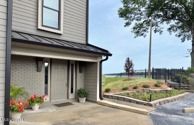 21 Breakers Ln, Ridgeland, MS 39157 - view of exterior entry featuring a standing seam roof, fence, metal roof, and brick siding
