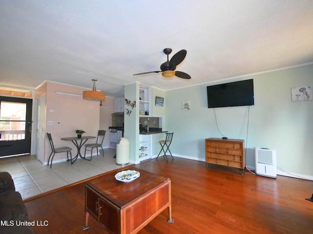 living room with hardwood / wood-style flooring, ceiling fan, and ornamental molding