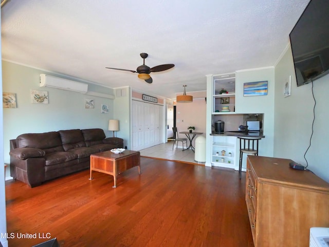 living room with an AC wall unit, ceiling fan, ornamental molding, and hardwood / wood-style flooring