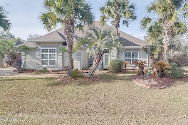 view of front of property with a shingled roof, a front lawn, and stucco siding